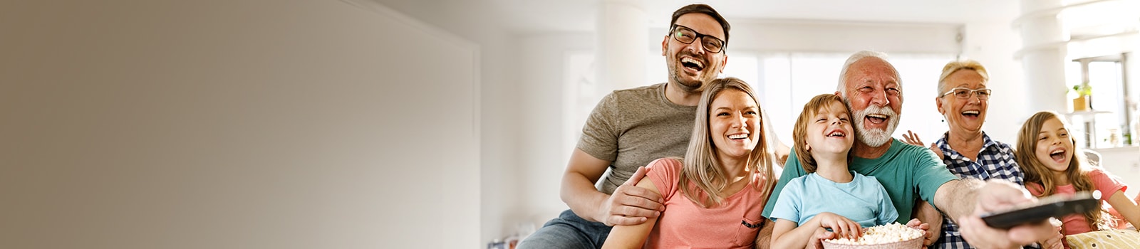 A family sits laughing while the grandfather points the remote outward.