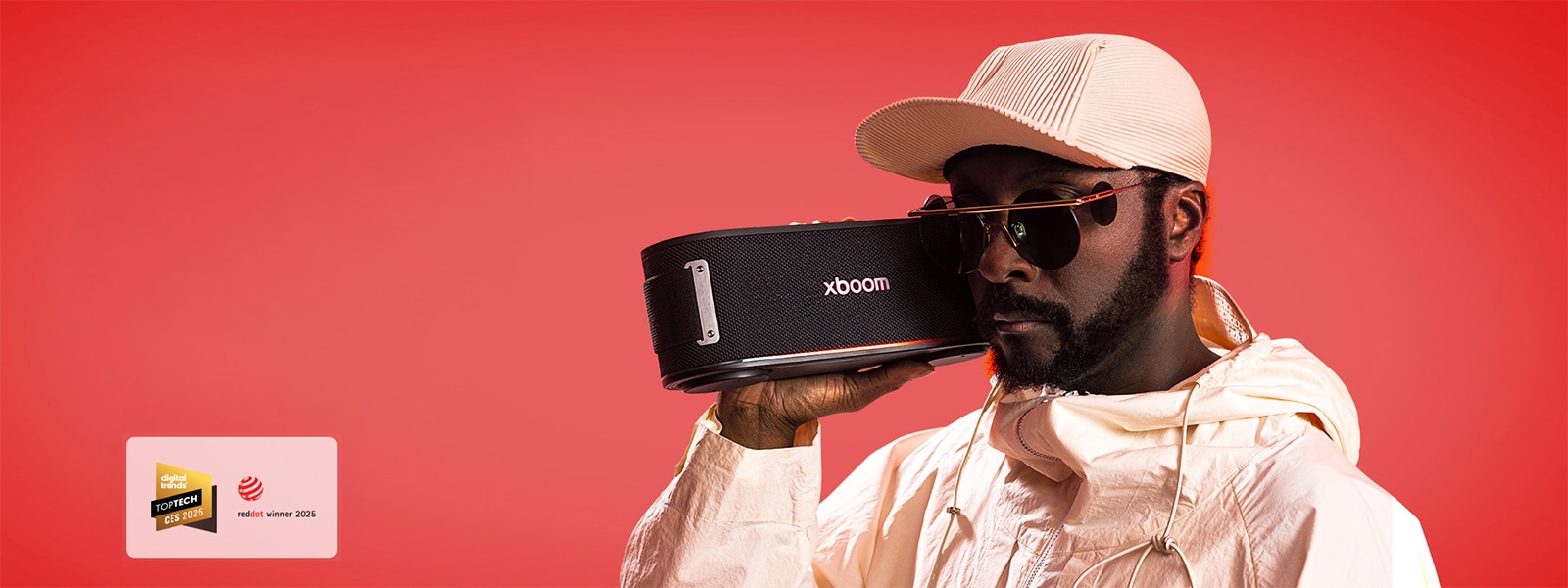 will.i.am in white outfit and sunglasses is holding xboom Bounce right next to his face.	