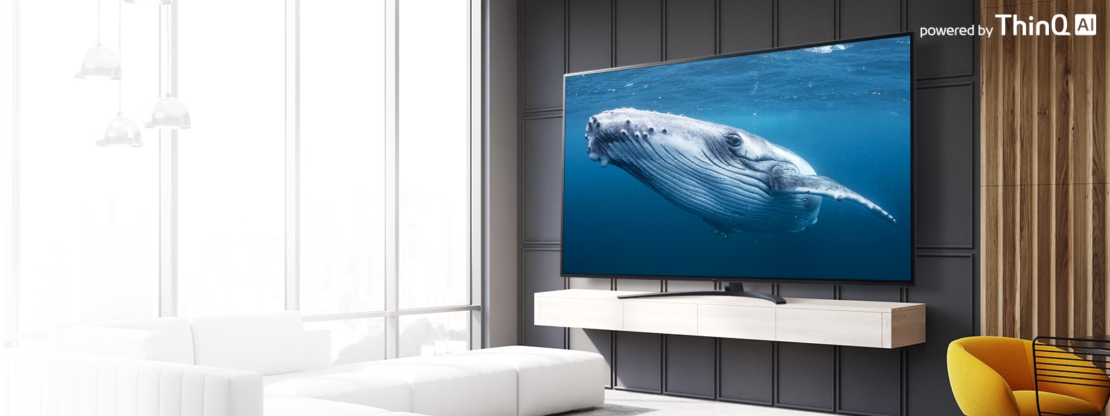 In a living room, there is a large screen TV displaying an image of a big whale in the sea. On the image, there is an introduction of a large screen TV on the left center and a powered by ThinQ AI logo on the upper right.