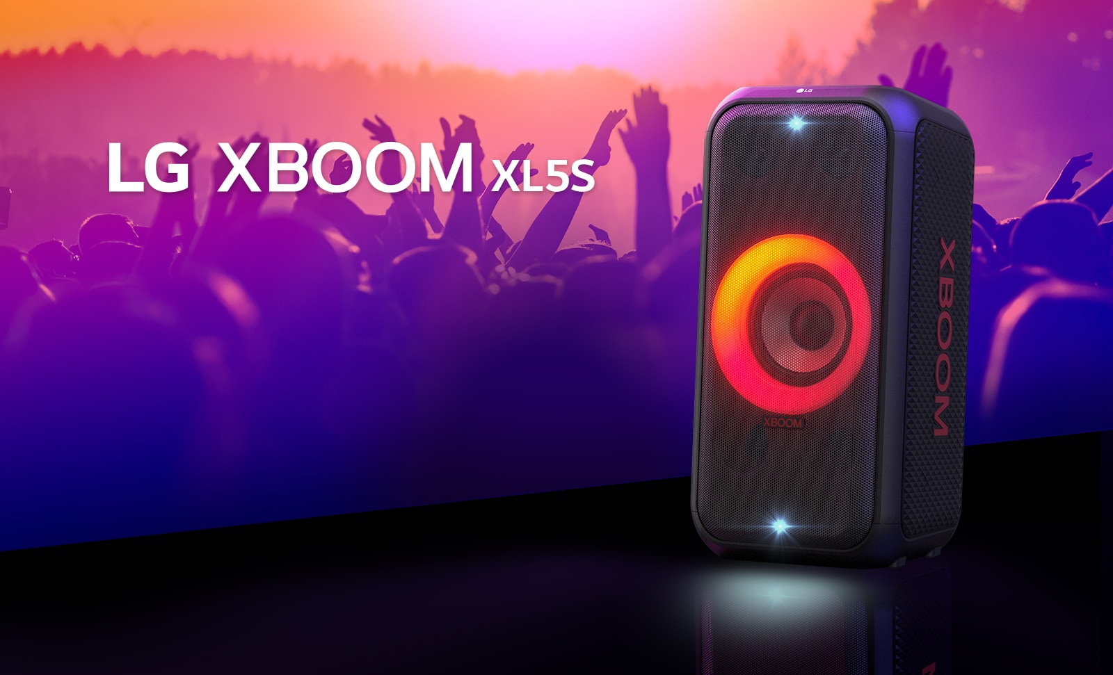 LG XBOOM XL5S is placed on the stage with red-orange gradient lighting is on. Behind the stage, people enjoy the music.