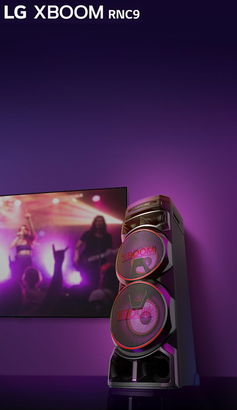 Vue en contreplongée du c?té droit de l’enceinte LG XBOOM RNC9 sur fond violet. L’éclairage du XBOOM est également violet. Et un écran de télévision diffuse un concert.