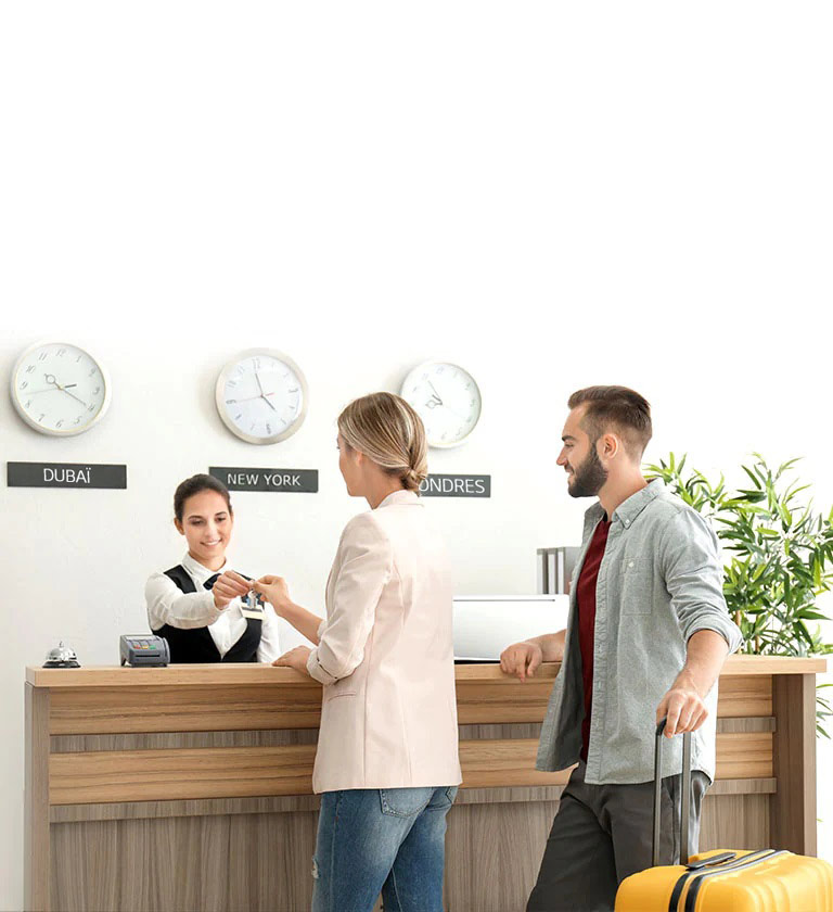 Image d’un couple s’enregistrant auprès d’un réceptionniste dans le hall d’un h?tel.