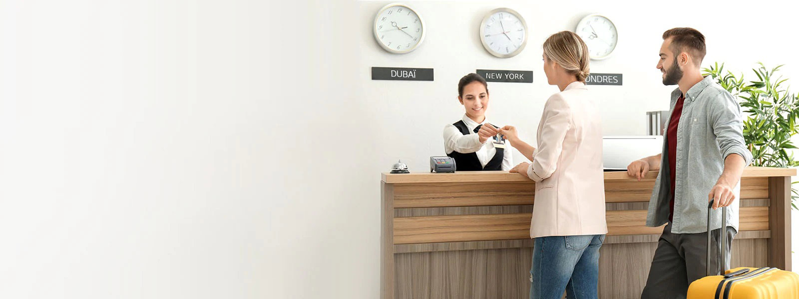 Image d’un couple s’enregistrant auprès d’un réceptionniste dans le hall d’un h?tel.