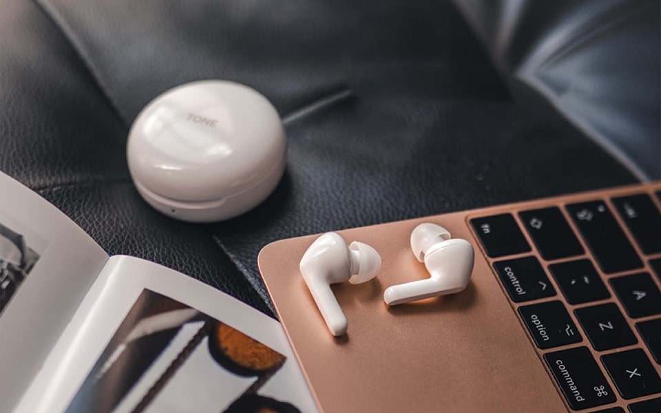 Une paire d'écouteurs repose sur un ordinateur portable avec un socle de chargement à proximité