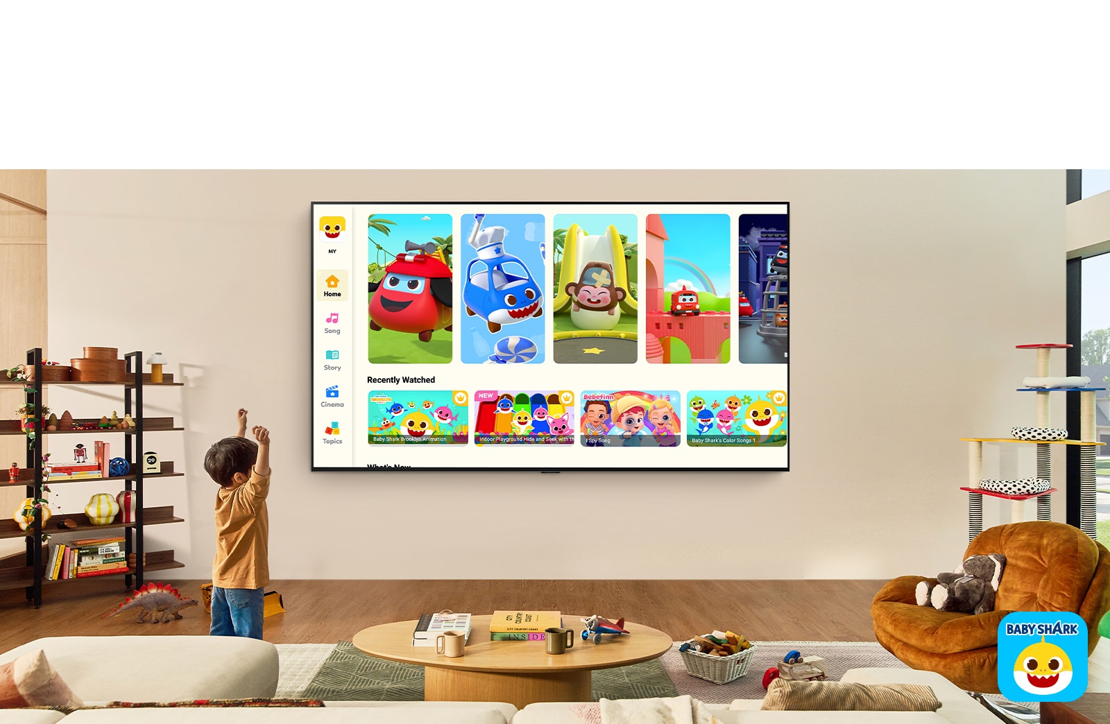 Un ni?o peque?o mira Pinkfong en una LG TV montada en la pared en una sala con juguetes para ni?os. 