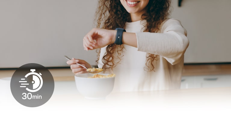 Una mujer en la mesa mira su reloj durante una comida ligera. Y un icono con 30 minutos escritos en él.