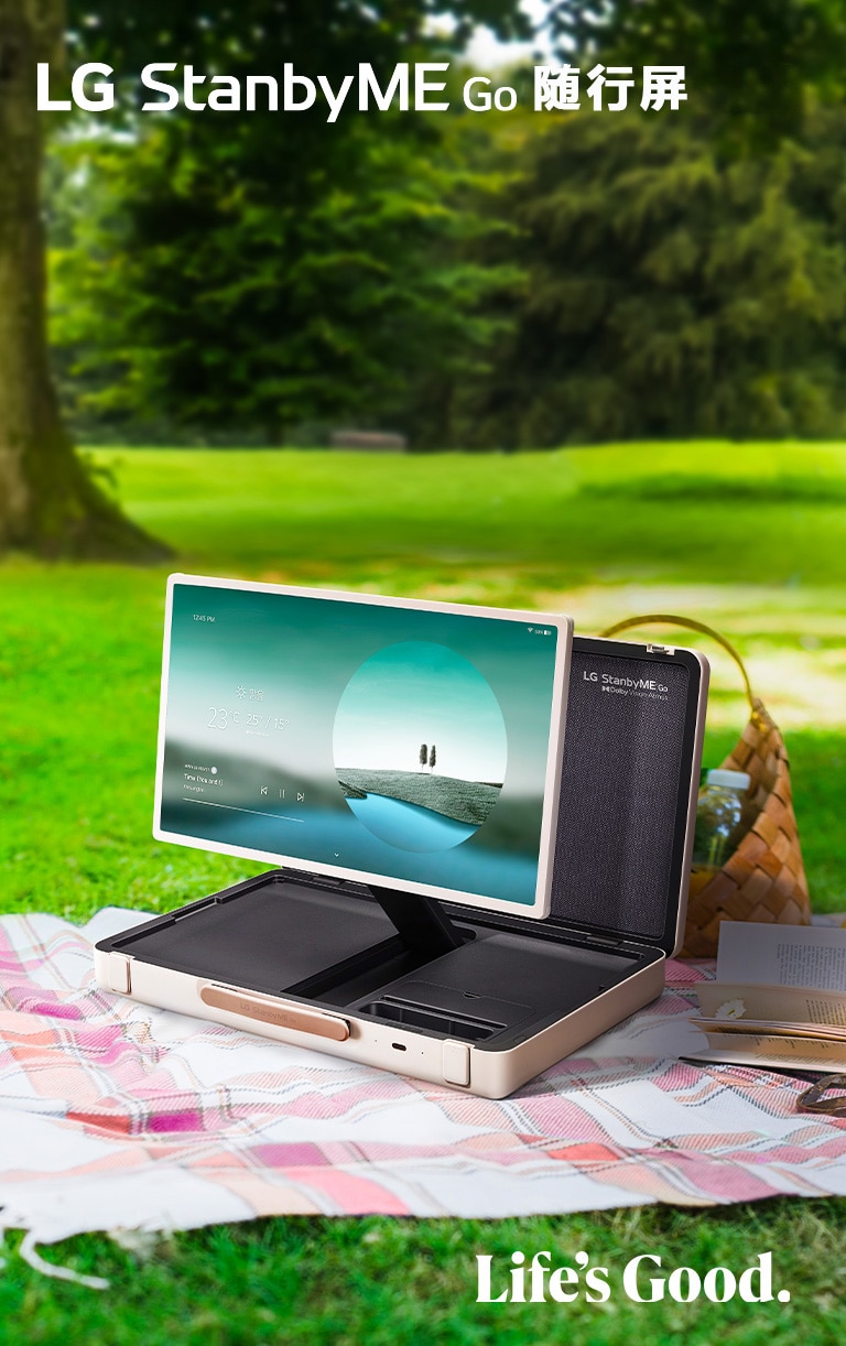 LG StanbyME Go is placed on a checkered picnic blanket with left side forward, displaying a weather themed home screen.