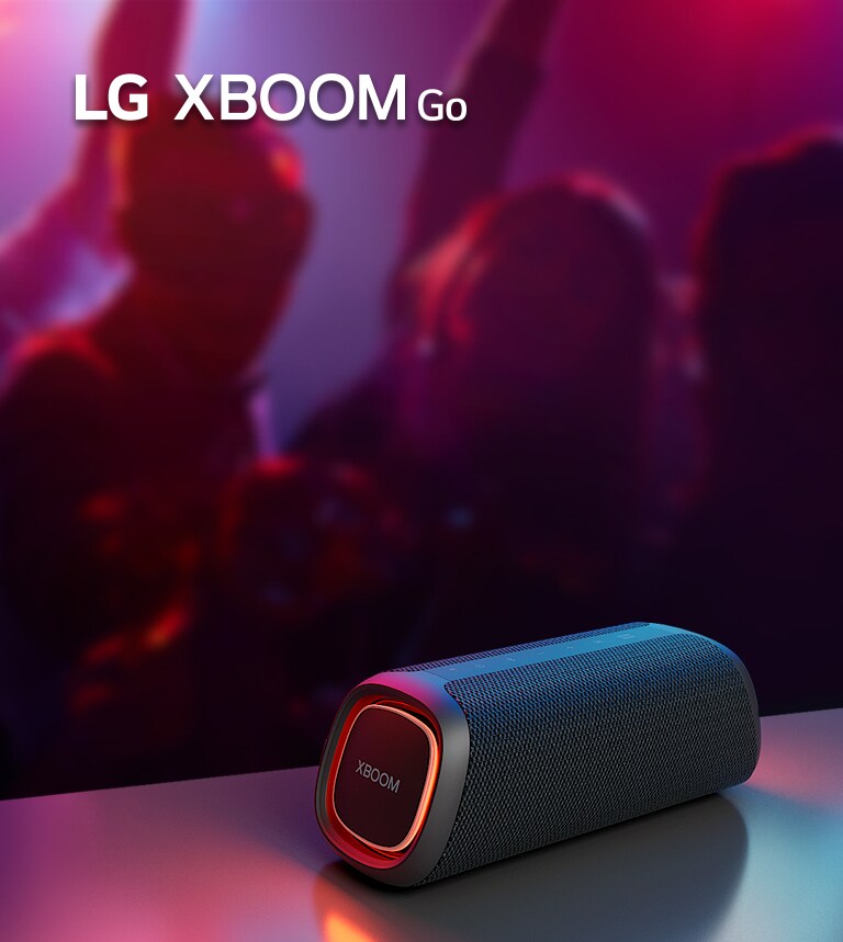 LG XBOOM Go XG5 放置在金屬桌子上，橙色燈亮起。人們在桌子后面享受音樂。