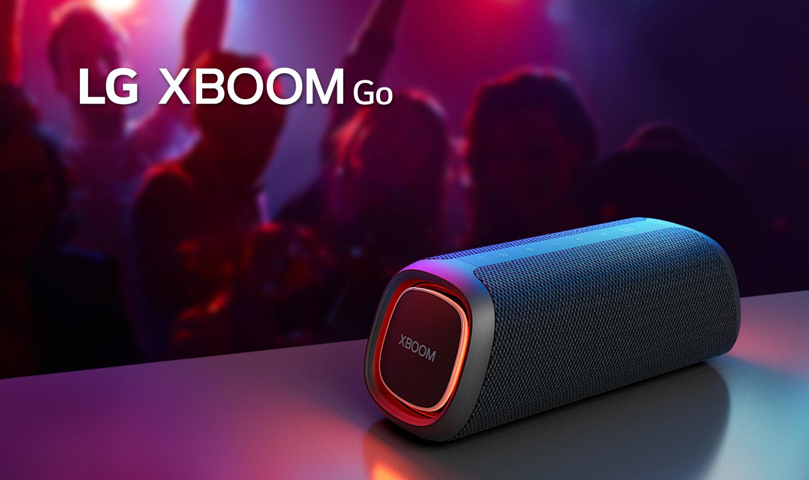 LG XBOOM Go XG7 放置在金屬桌子上，橙色燈亮起。人們在桌子后面享受音樂。