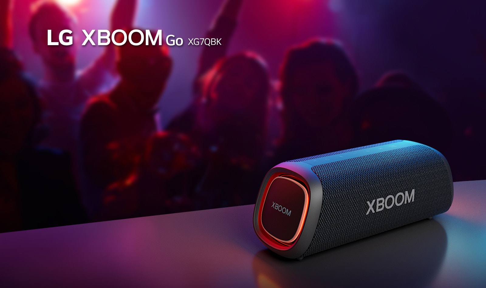 LG XBOOM Go XG7 放置在金屬桌子上，橙色燈亮起。人們在桌子后面享受音樂。