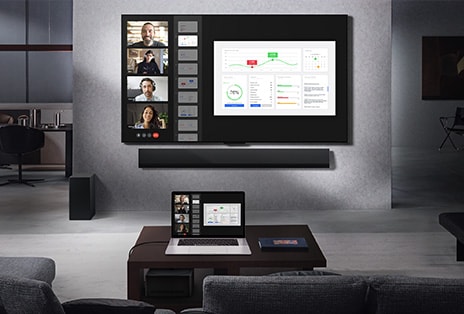 Wohnzimmer mit Blick von der Couch auf einen an der Wand montierten LG True Wireless TV und eine LG Soundbar. Auf dem Couchtisch steht ein Laptop, der mit der Zero Connect Box verbunden ist. Diese befindet sich kaum sichtbar unter dem Tisch. Der Laptop-Bildschirm, auf dem ein Live-Videoanruf l?uft, wird kabellos auf den Fernsehbildschirm gespiegelt. Der gesamte Raum wirkt aufger?umt und ist frei von Kabelgewirr.