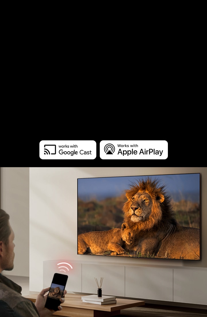 Uma LG TV montada em uma parede de uma sala de estar, exibindo um le?o e seu filhote. Um homem sentado em primeiro plano segura um smartphone que exibe a mesma imagem de le?es. Um gráfico de três barras curvas em vermelho neon é exibido logo acima do smartphone, apontando para a TV.