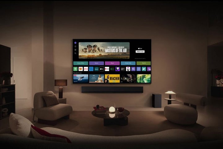 Um close da tela de uma LG TV mostrando os bot?es Home Office, Jogos e Música sobre um banner do Masters of the Air, e a vis?o é ampliada para mostrar a TV montada na parede de uma sala de estar. Os seguintes logotipos s?o exibidos na tela da TV: LG Channels, Netflix, Prime Video, Disney TV, Apple TV, YouTube, Spotify, Twitch, GeForce Now e Udemy.