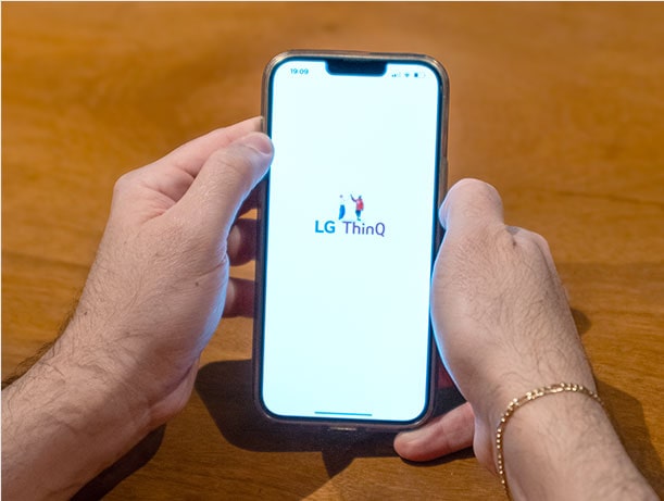 Uma fotografia de pai a lidar com o telemóvel e a iniciar uma aplica??o. O nome de uma aplica??o é ThinQ.