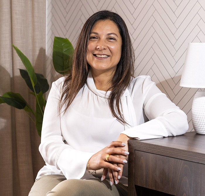 Rosana sorrindo com os bra?os sobre a mesa, vestindo uma camisa branca.