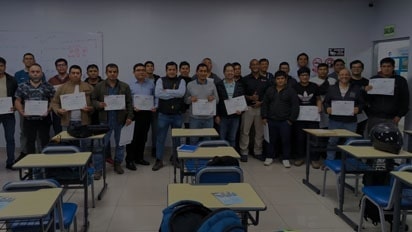 No espa?o onde acontece o treinamento, diversas pessoas posam com certificados nas m?os.