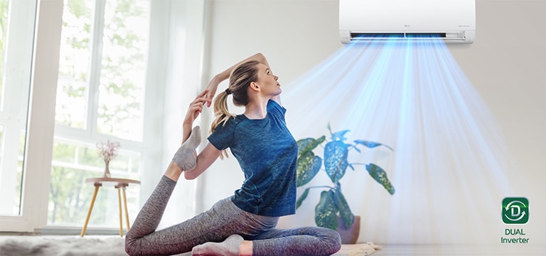  Mulher praticando ioga em uma sala bem iluminada, com ar-condicionado LG Dual Inverter ao fundo soprando ar frio.