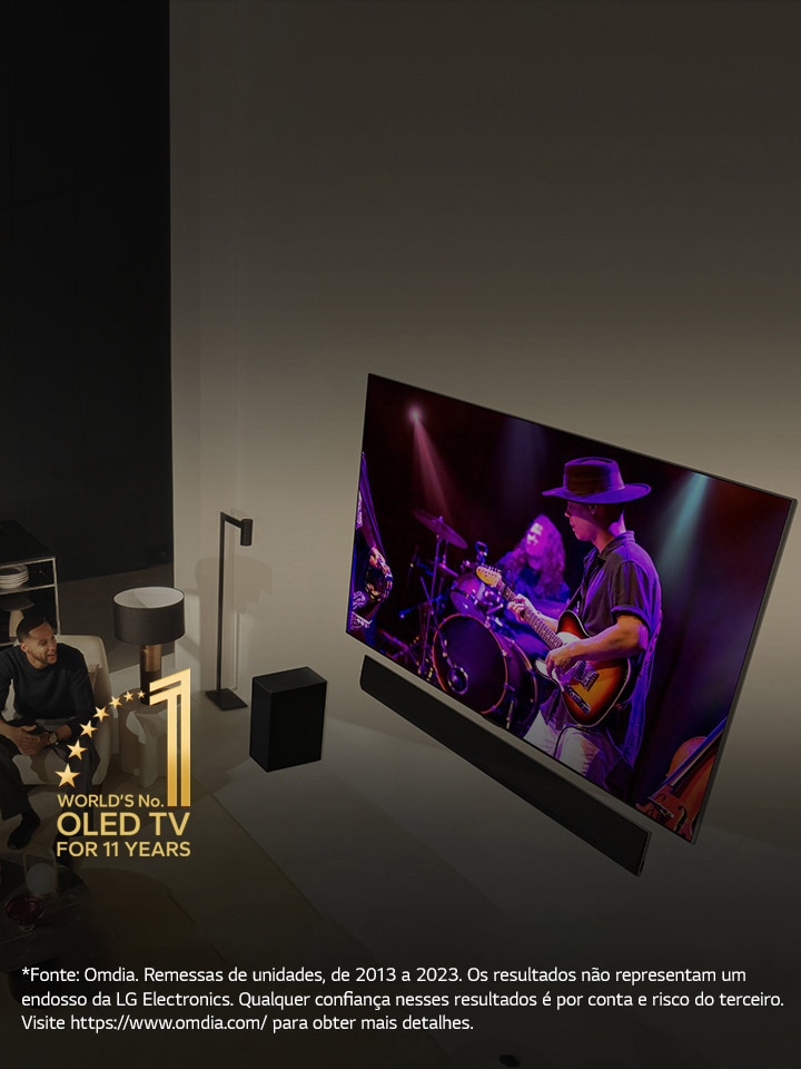 Uma perspectiva aérea de um homem e uma mulher assistindo a um concerto em uma grande TV OLED em um apartamento moderno. O emblema “A OLED TV número 1 do mundo por 11 anos” é exibido na imagem. Um aviso diz: “Fonte: Omdia. Remessas de unidades, de 2013 a 2023. Os resultados n?o representam um endosso da LG Electronics. Qualquer confian?a nesses resultados é por conta e risco do terceiro. Visite https://www.omdia.com/ para obter mais detalhes.”