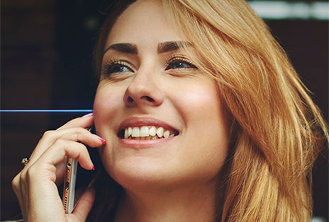 De gauche à droite?: Une femme parle au téléphone à l’extérieur et porte les écouteurs?T80S. Ils filtrent les bruits de fond et l’autre femme ne peut entendre clairement que sa voix.
