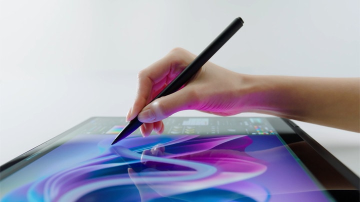 Cette vidéo montre la main d’une femme tenant un stylet, touchant délicatement l’écran d’un ordinateur portable en mode tablette pour dessiner avec fluidité.