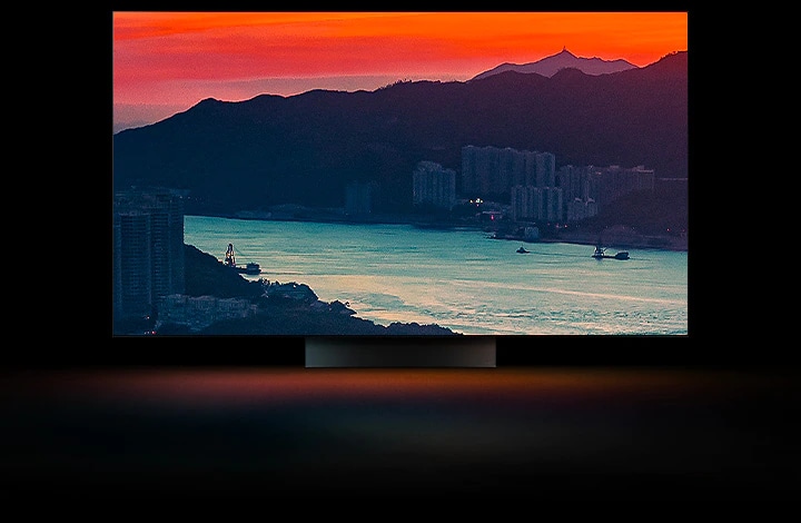 Une vue aérienne d’une ville c?tière avec de la circulation sur un pont pendant que le soleil se lève sur tout l’écran. L’image se recadre et s’affiche sur un téléviseur OLED de LG avec les couleurs d’origine inchangées.