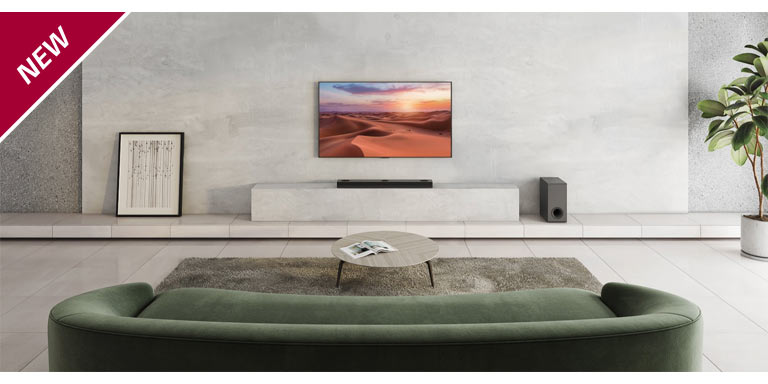 Ein Fernseher h?ngt an einer wei?en Wandverkleidung in einem Wohnzimmer. Darunter steht eine LG Sound Bar auf einem TV-Regal. Auf dem Boden rechts vom Regal steht ein kabelloser Subwoofer. Auf Beistelltischen links und rechts hinter dem Sofa stehen zwei externe Lautsprecher. In der linken oberen Ecke steht ?NEU“.
