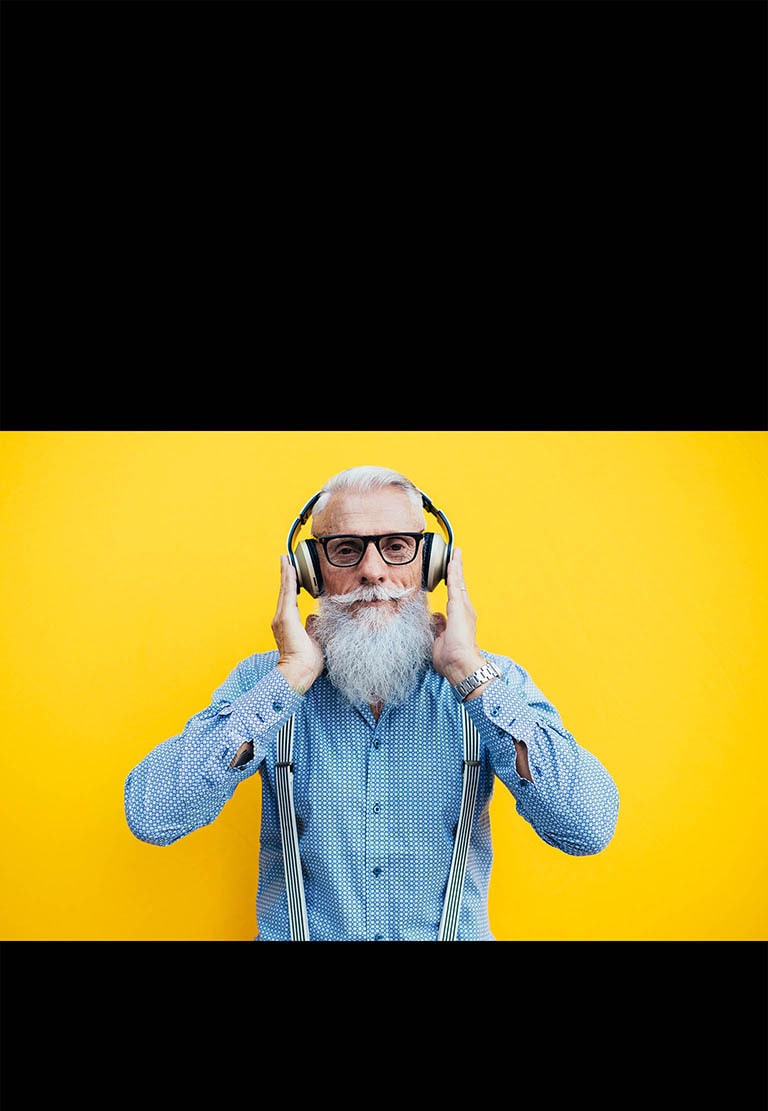 Ein ?lterer Mann steht vor einer gelben Wand und tr?gt ein Headset.