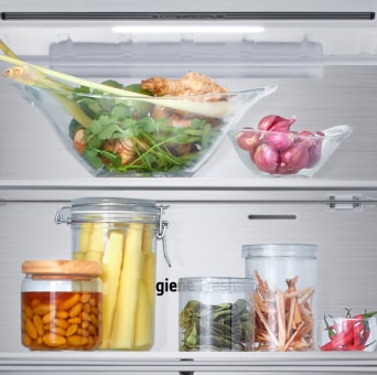 Vista de cerca del estante inferior del congelador del frigorífico LG con alimentos varios en recipientes de cristal.