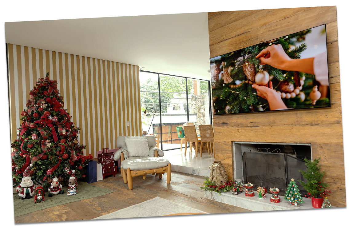 Un árbol de Navidad está decorado en un cálido entorno festivo, mientras el televisor LG OLED muestra un video de decoración navide?a en la sala de estar.