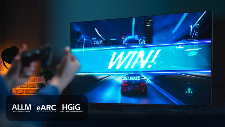 Un juego de carreras de coches en la línea de meta, con el cartel que dice "?GANA!", mientras el jugador agarra el joystick del juego. Los logotipos de eARC y HGiG se encuentran en la esquina inferior izquierda.