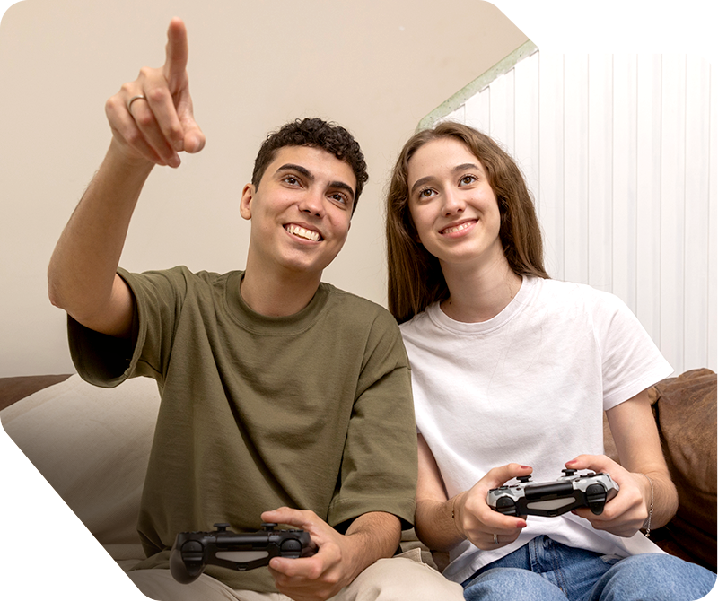 Foto frontal de Bruno y su novia. Ambos sonriendo, sosteniendo controles de videojuegos. Bruno se?alando la LG C4 OLED TV.