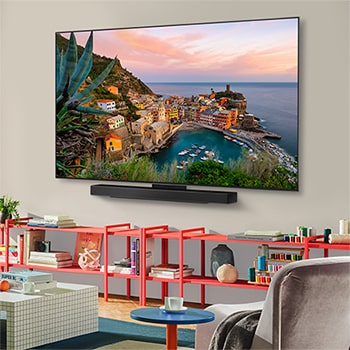 ?iroky pohled na stylovy a barevny obyvací pokoj. LG OLED evo AI C5 4K Smart TV je p?ipevněn na stěně a pod ním je umístěn LG Soundbar. Design televizoru dob?e zapadá do prostoru. Na televizní obrazovce je barevná kresba. 