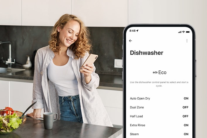  ?ena se dívá na sv?j mobilní telefon v kuchyni a smartphone ukazuje nastavení personalizace v aplikaci ThinQ?.