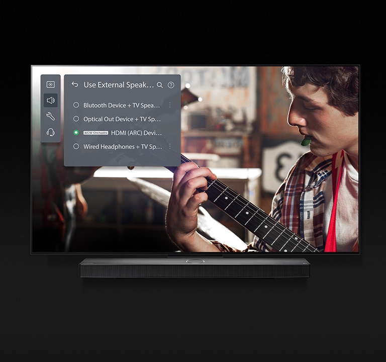 Obrázek televizoru LG OLED se soundbarem. Na obrazovce se p?ehrává video chlapce, ktery hraje na kytaru, a?naho?e se zobrazuje nastavení re?imu soundbar.