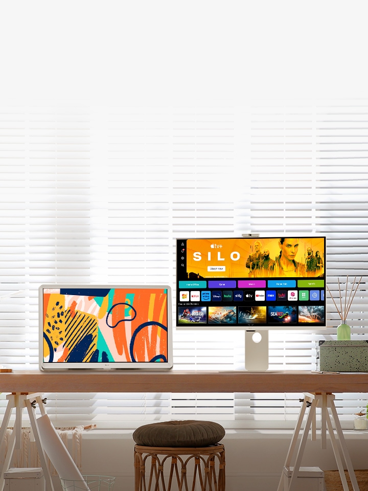 Světlá scéna v?obyvacím pokoji ukazuje chytry monitor a?televizor LG Room&TV umístěné na stole u?okna.