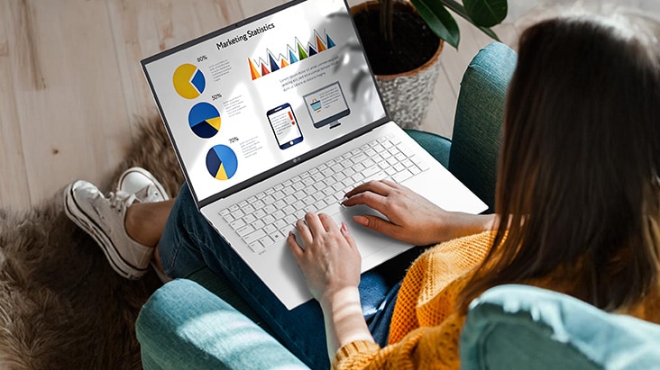 Eine Person sitzt bequem auf einem Stuhl und verwendet einen Laptop, auf dem eine Pr?sentation mit Diagrammen und Grafiken angezeigt wird. Eine Animation veranschaulicht den blendfreien Bildschirm, indem sie zeigt, dass selbst bei direkter Sonneneinstrahlung keine Lichtreflexion auftritt.