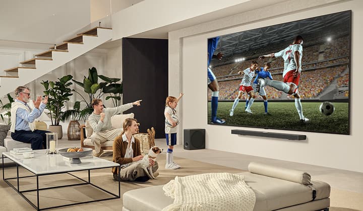 Eine Familie ist um ihren ultragro?en LG TV versammelt und sieht sich auf dem riesigen Bildschirm ein spannendes Fu?ballspiel an.