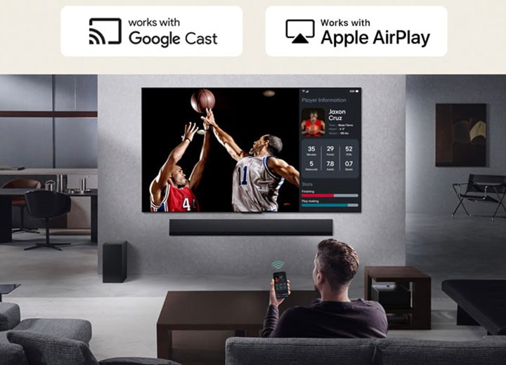 Person im Wohnzimmer, die ein Telefon in der Hand h?lt. Auf dem Telefon zeigt ein übertragungssymbol an, dass der Bildschirm des Telefons auf dem Fernseher gespiegelt wird. Im Fernsehen l?uft ein Basketballspiel, daneben zeigt ein Spiegelbildschirm Spielerstatistiken an.