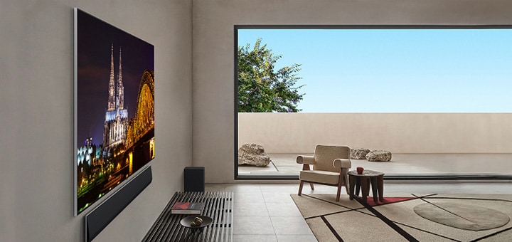 Wohnzimmer mit einem an der Wand befestigten LG OLED evo G5 TV mit LG Soundbar von der Seite aus betrachtet. Aus diesem Winkel sind das Gallery Design und die bündig an die Wand passenden Blenden gut zu erkennen. 