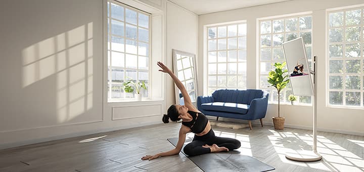 Frau in ihrem ger?umigen Zuhause macht Yoga. Neben ihr steht der LG StanbyME TV auf einem Standfu?. Das Ger?t befindet sich in vertikaler Ausrichtung und gibt das Yoga-Unterweisungsvideo wieder, dem die Frau folgt.