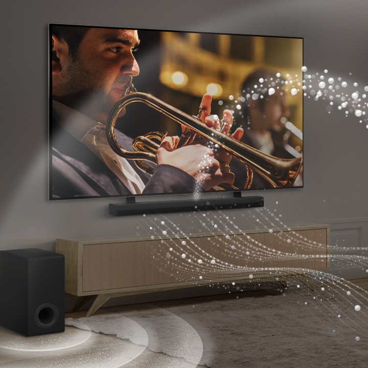 LG Soundbar, LG TV und ein Subwoofer stehen in einer modernen Stadtwohnung. Die LG Soundbar strahlt Schallwellen aus wei?en Tr?pfchen aus, die den Raum füllen, und ein Subwoofer erzeugt einen Klangeffekt von unten. Gemeinsam erzeugen sie einen Kuppeleffekt im Raum.
