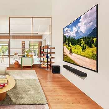 Schr?ge Ansicht des wandmontierten LG QNED86 AI 4K Smart Fernsehers in einem modernen Wohnbereich, die sein schlankes Design und eine Radfahrerszene auf dem Bildschirm zeigt.