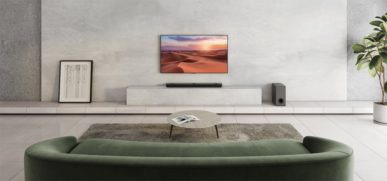 Zu sehen ist ein Fernseher, der ein Naturbild zeigt. Eine Soundbar, ein Subwoofer und 2 hintere Lautsprecher befinden sich in einem weitr?umigen Wohnzimmer. Von der Soundbar geht eine Welle mit Gittermuster aus, die bildlich darstellt, wie das gesamte Wohnzimmer vermessen wird.