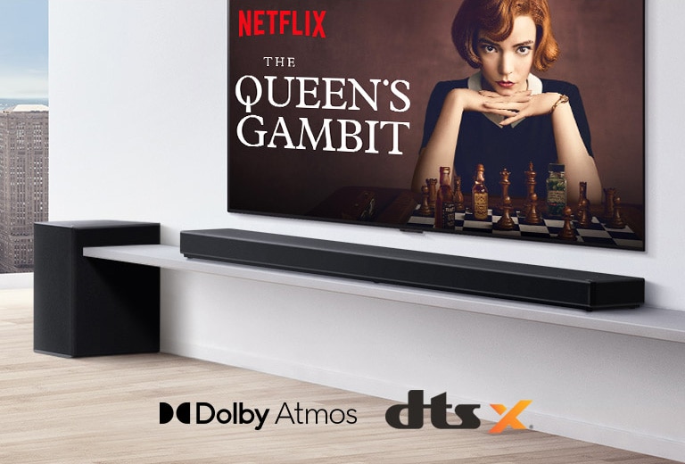An der Wand befestigter TV.  Ein Poster einer TV-Sendung ist auf dem Bildschirm zu sehen. Die LG Soundbar steht unter dem TV auf einem wei?en Regal mit Subwoofer direkt daneben. Die Logos von Dolby Atmos und DTS:X werden in der Mitte unten im Bild angezeigt.