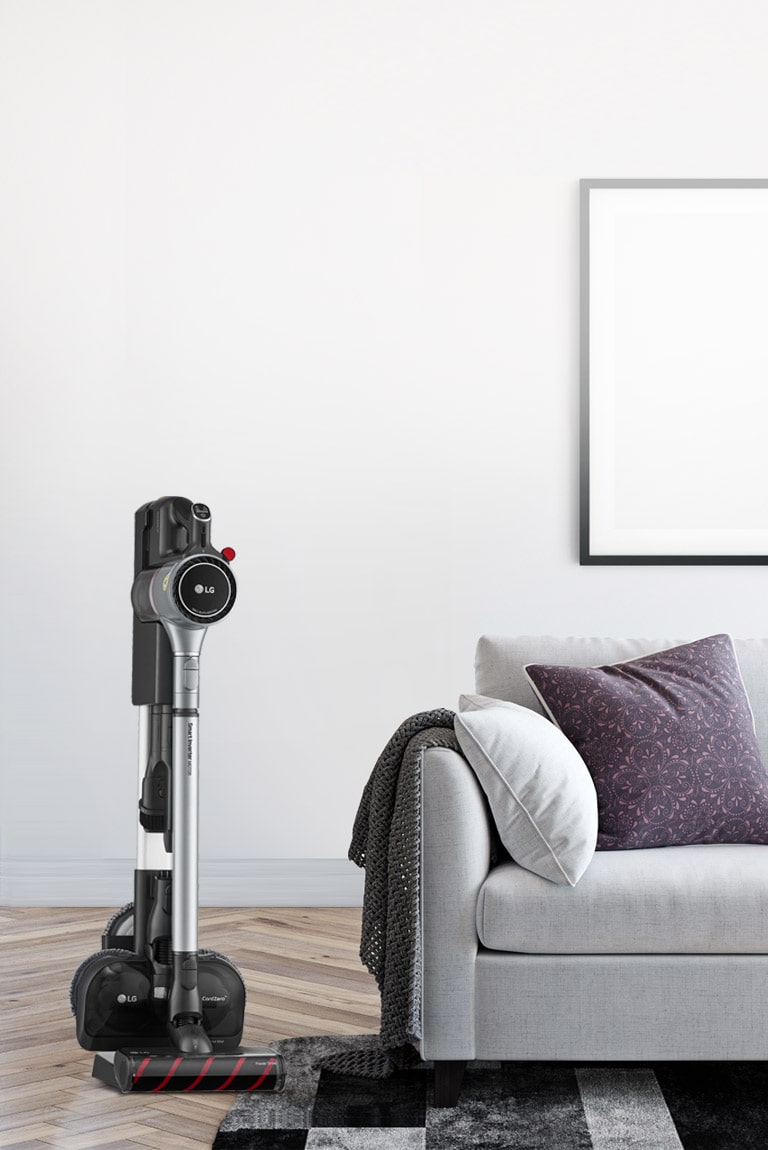 Der CordZero A9 Kompressor-Staubsauger steht in der Ladestation in einem Wohnzimmer in der N?he des Sofas.