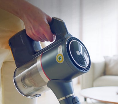 Man sieht die Hand einer Frau, die bequem den Griff des Staubsaugers ergreift, w?hrend sie das Wohnzimmer reinigt.