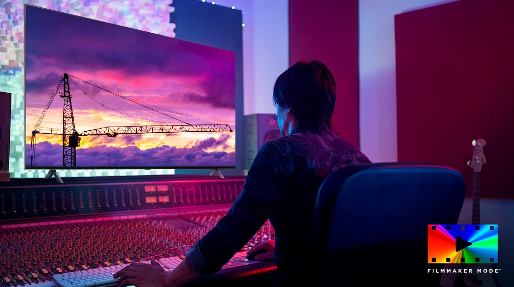 Ein Filmregisseur blickt auf einen gro?en TV-Monitor und bearbeitet etwas. Der Fernsehbildschirm zeigt einen Kran vor einem violetten Himmel. Das Logo des FILMMAKER MODE befindet sich in der unteren rechten Ecke.