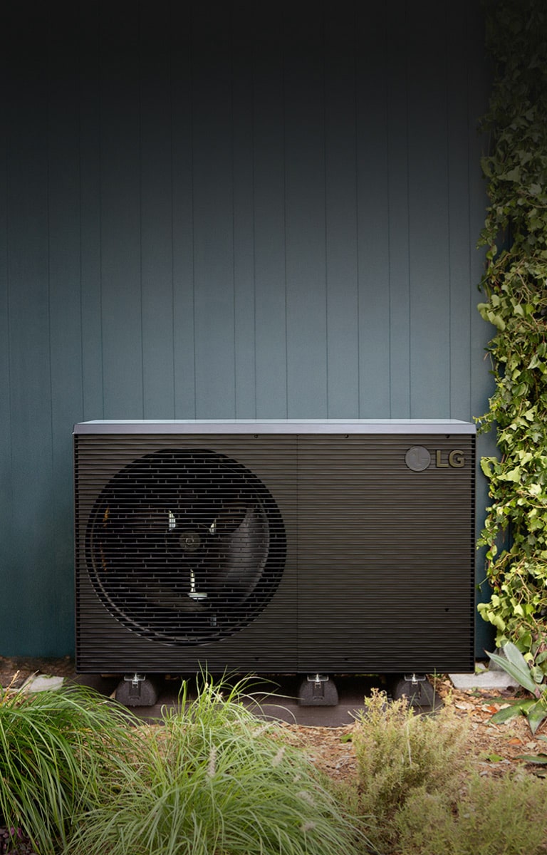 LG Luft/Wasser W?rmepumpe THERMA V R290 Monobloc, schwarze Au?eneinheit ist auf der grünen Au?enwand dargestellt.