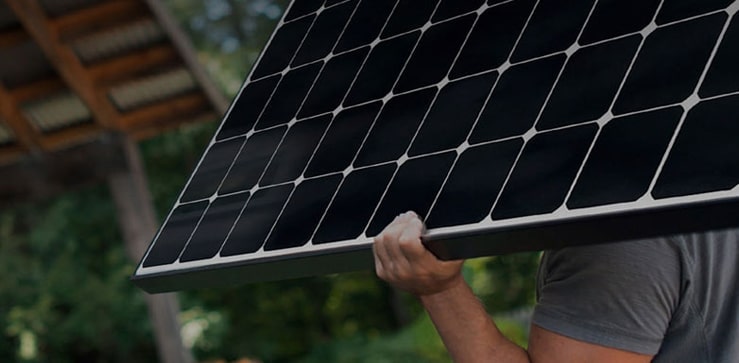 Ein Installateur tr?gt ein LG Solarmodul auf der Schulter