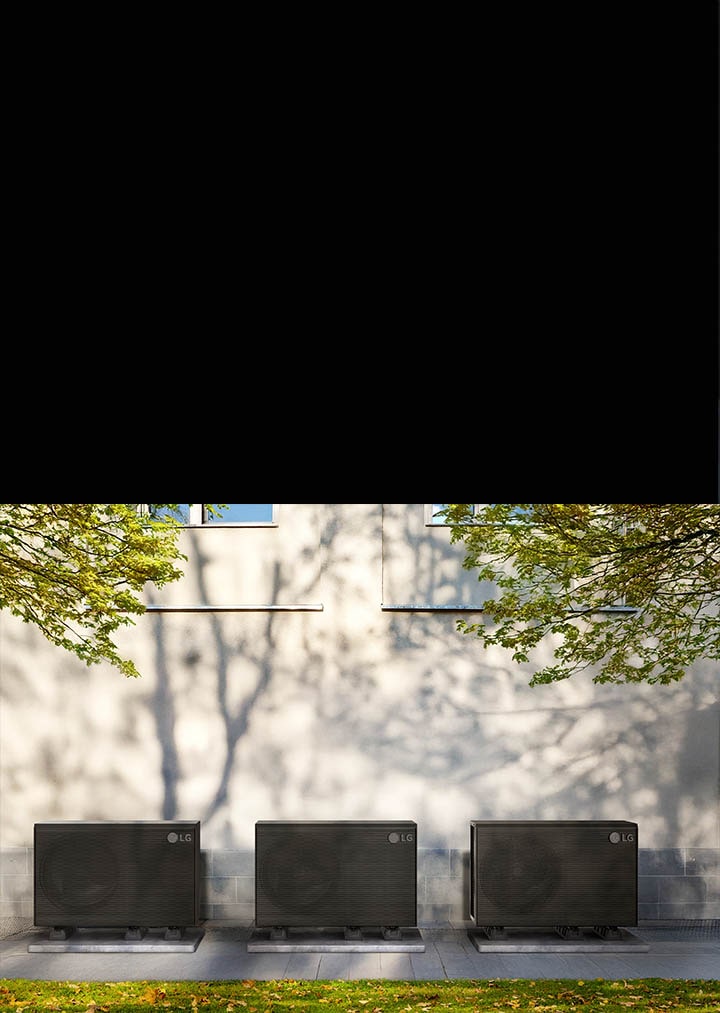 Et sort LG THERMA V-produkt er anbragt i haven omkring et hus, og en kvinde med en kasse g?r forbi foran det.